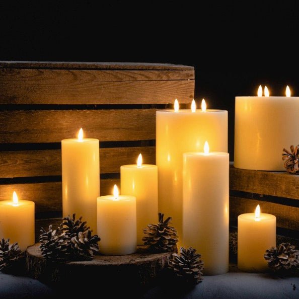 varying sizes of LED Flameless candles, all lit and displayed with pine cones