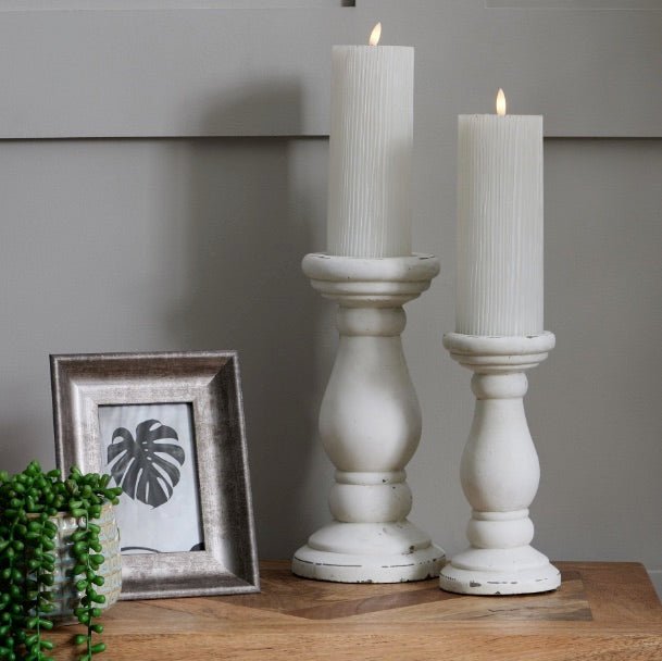 two LED ribbed candles on stone candlesticks next to distressed silver photo frame