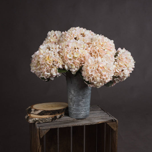 several stems of Autumn White Hydrangea in silver flower bucket on wooden crate