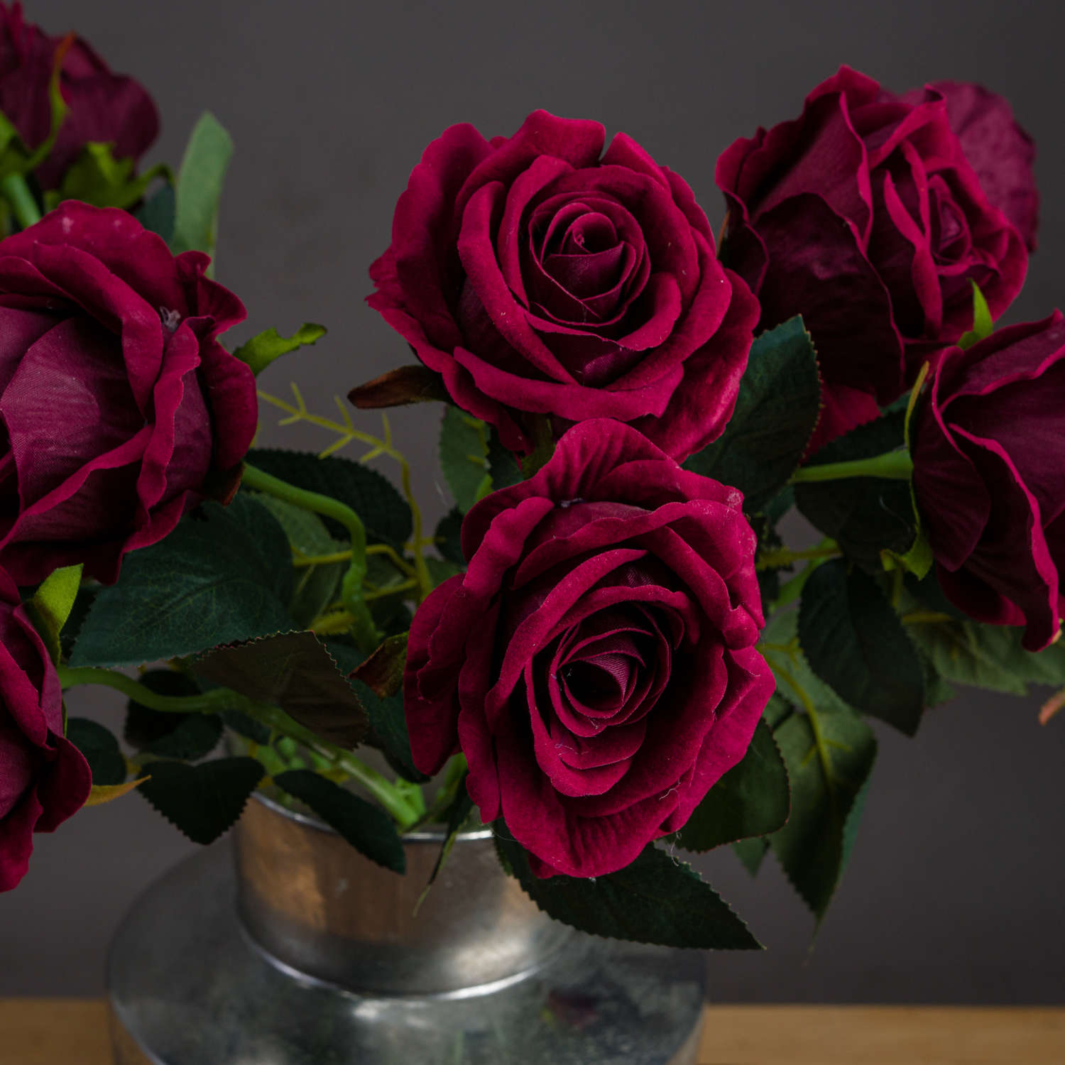 several single stems of deep red rose in silver vase