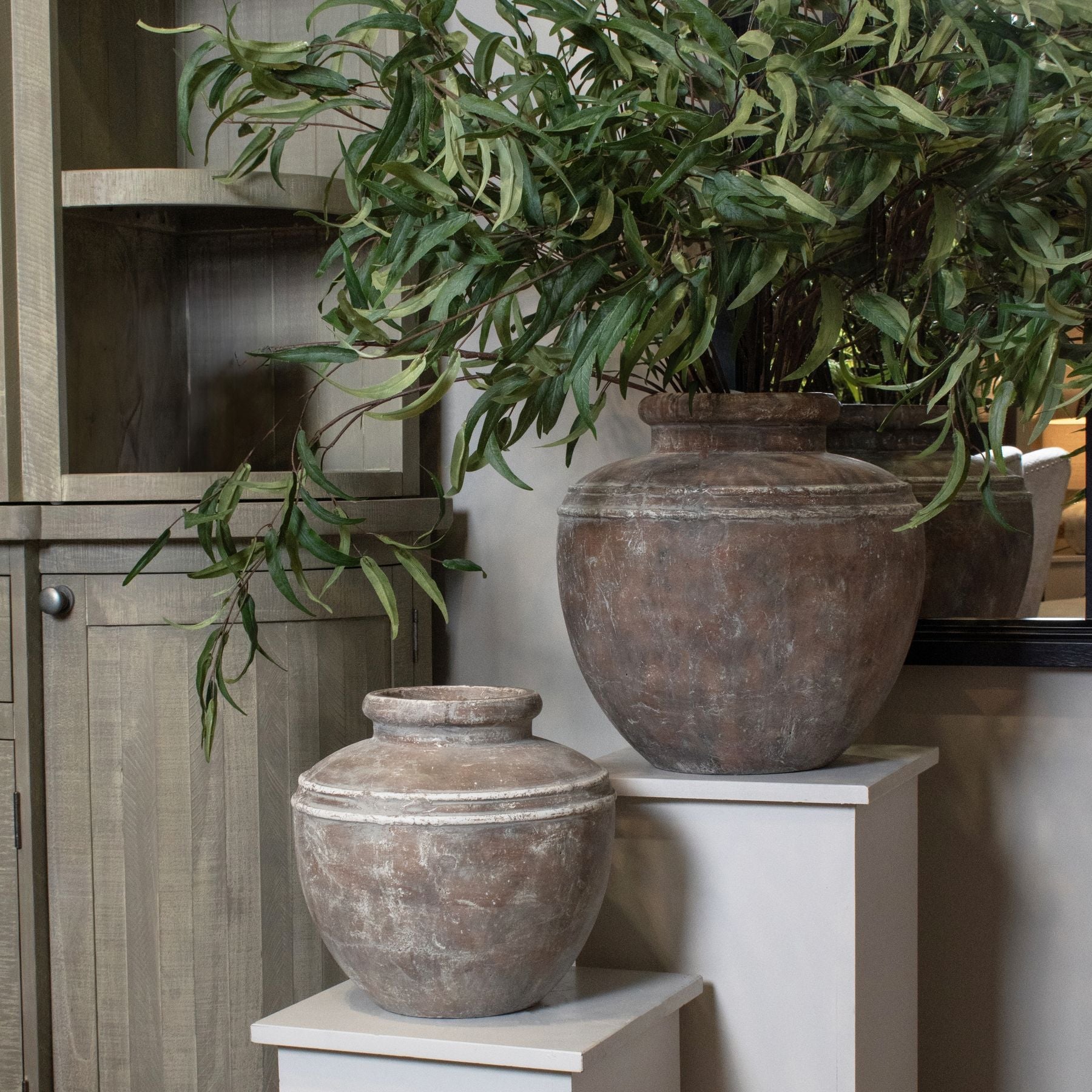 Small and large water pot vases, the large with artificial branches in