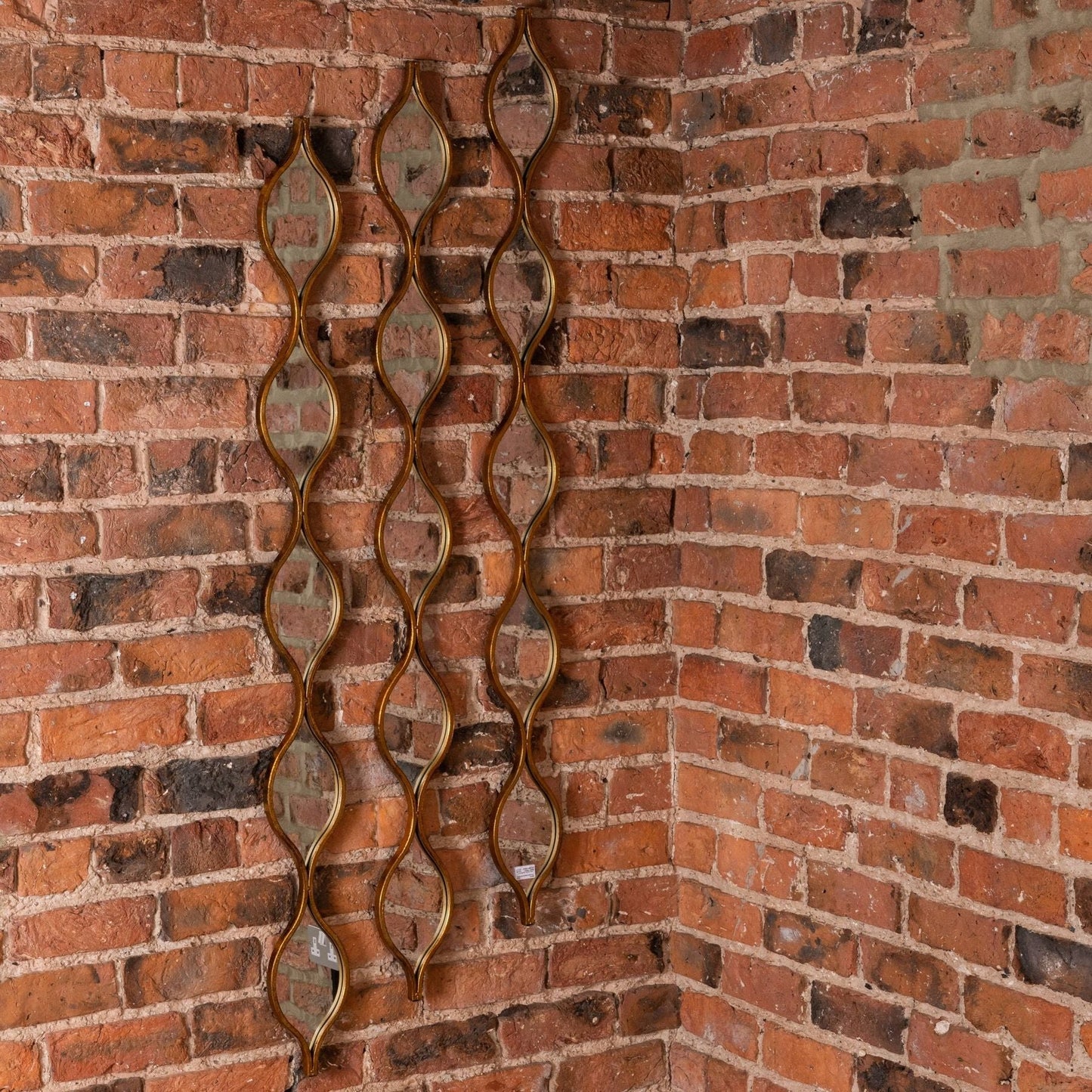 three wall mirrors placed at different heights to create a display on a brick wall