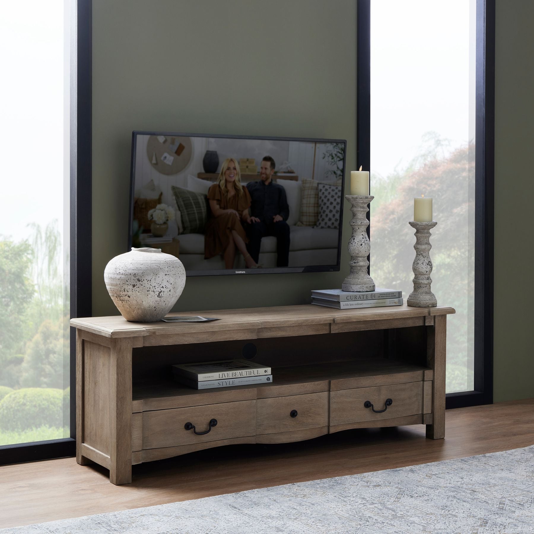 small aged stone regal vase on cotswold TV cabinet, two aged stone candle holders are on decorative books to the opposite end