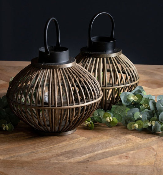 Small and large bamboo lanterns on table dressed with eucalyptus spray in between