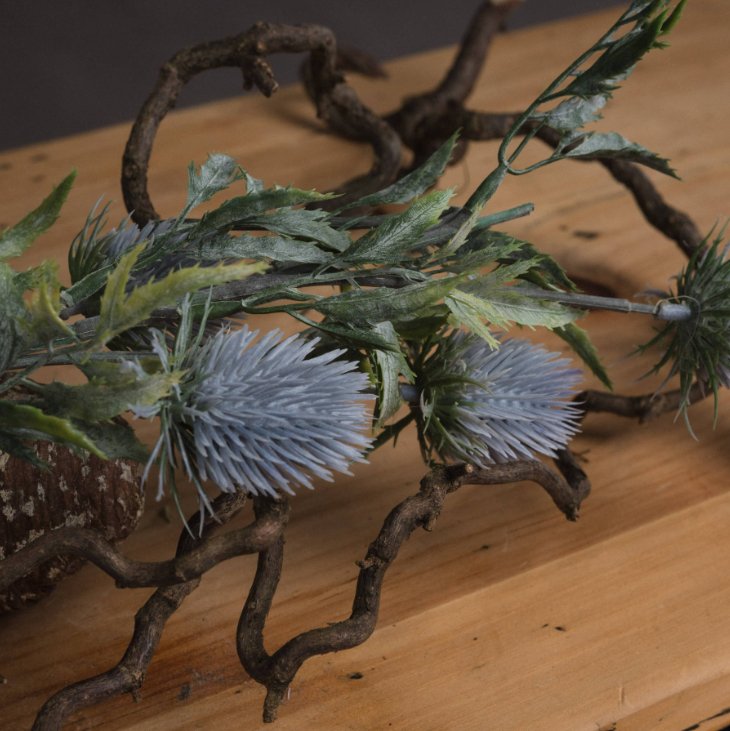 blue thistles laid on branches, close up detail