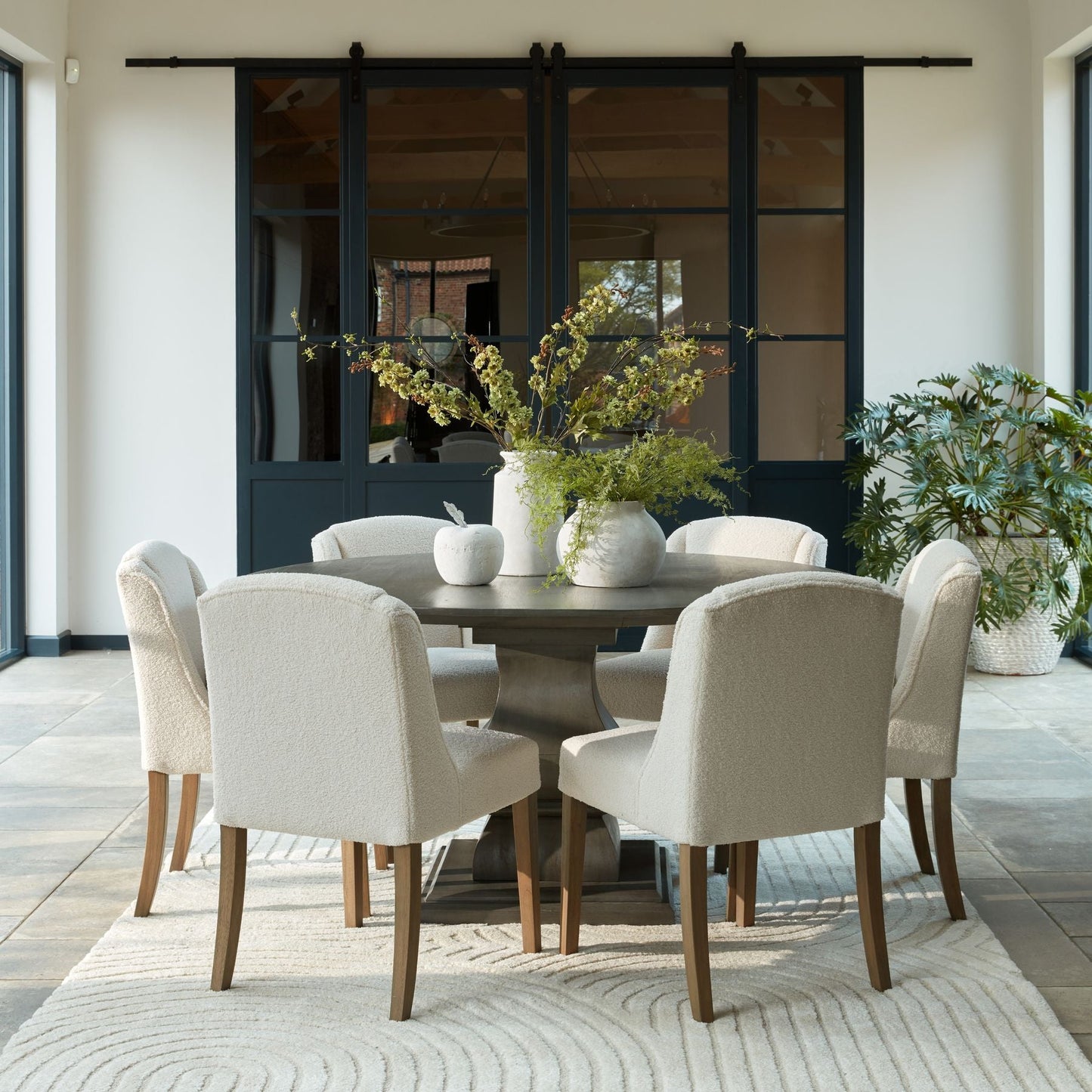 lifestyle image of 6 chelsea boucle dining chairs around the cotswold round pedestal dining table