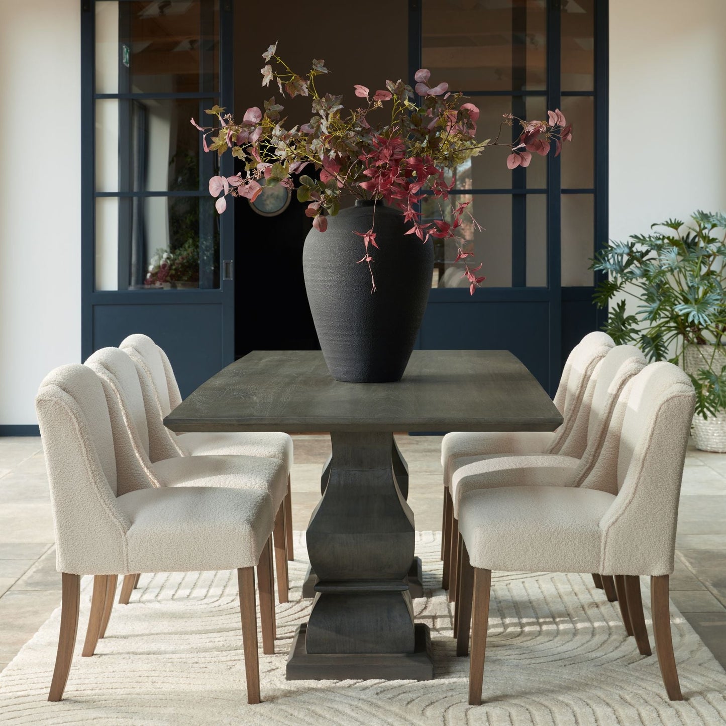 lifestyle image of three chairs down ether side of the pedro pedestal rectangular dining table