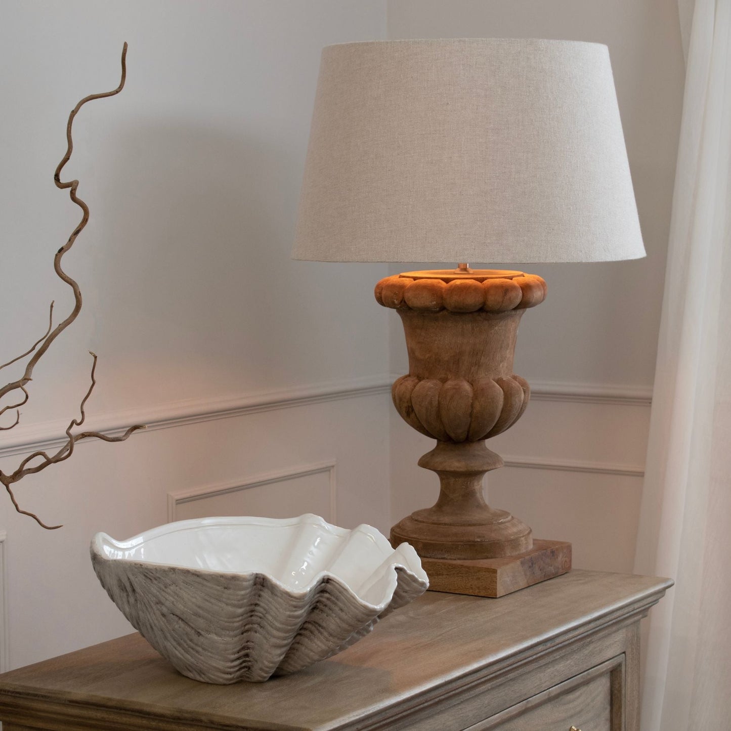 clam shell bowl next to wooden table lamp with linen shade