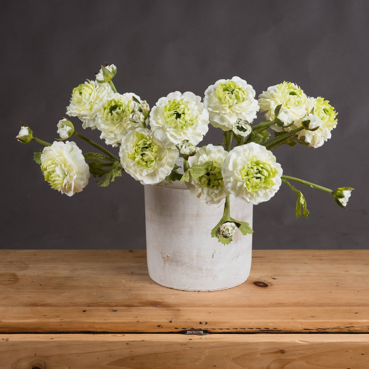 bunch of ranunculus sprays in stone vase