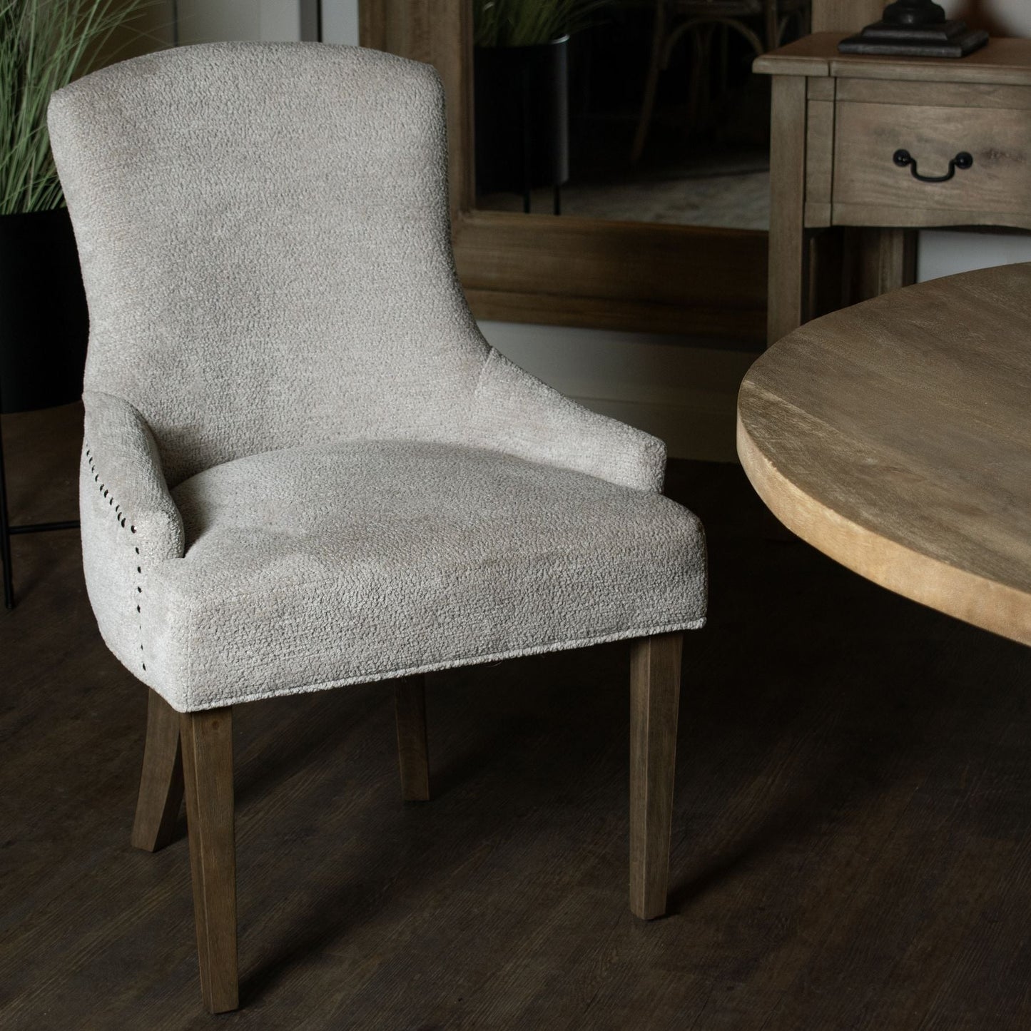 lifestyle image if headley dining chair in taupe woven fabric next to round wooden dining table