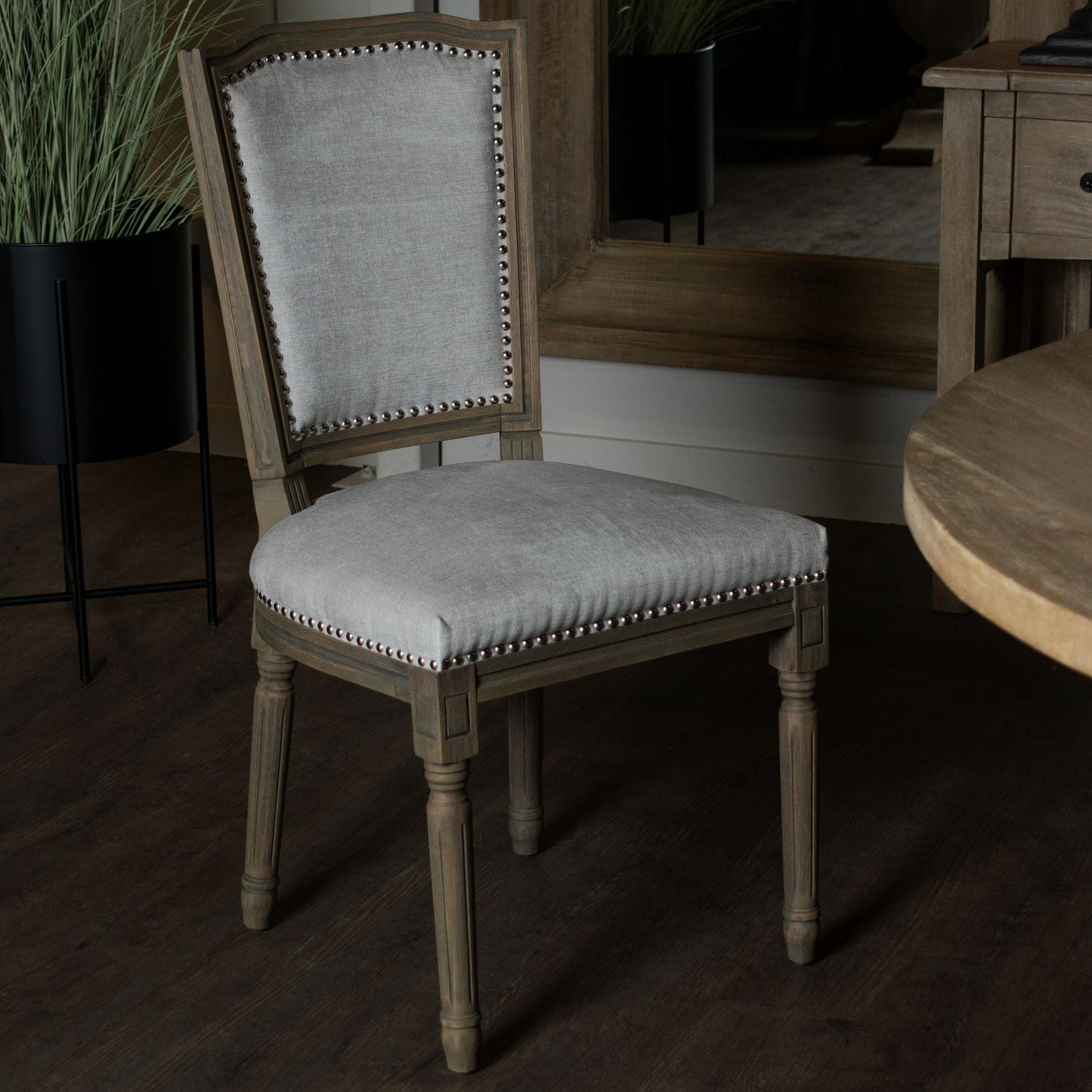 lifestyle image of the henley dining chair, the edge of the Cotswold round pedestal dining table can be seen to the right of the screen