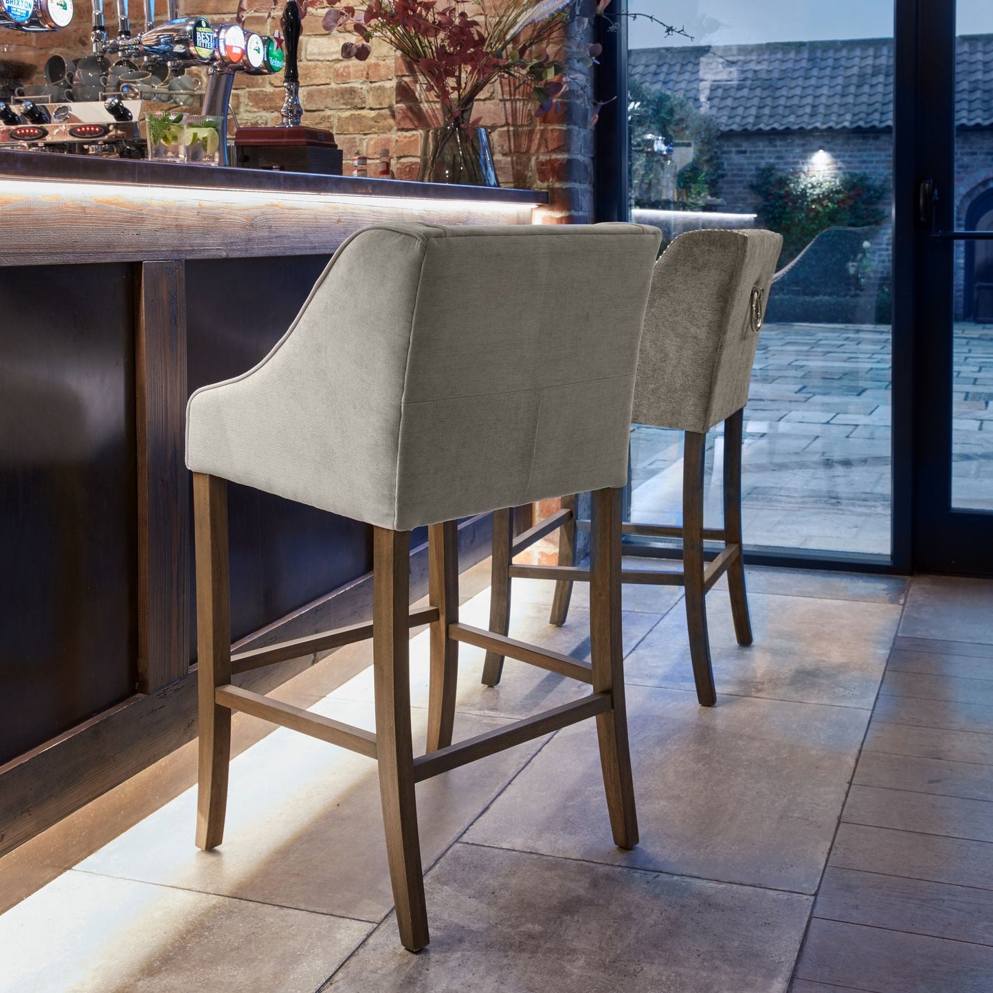 lifestyle image of the back of marsden bar stool against a dark wood bar