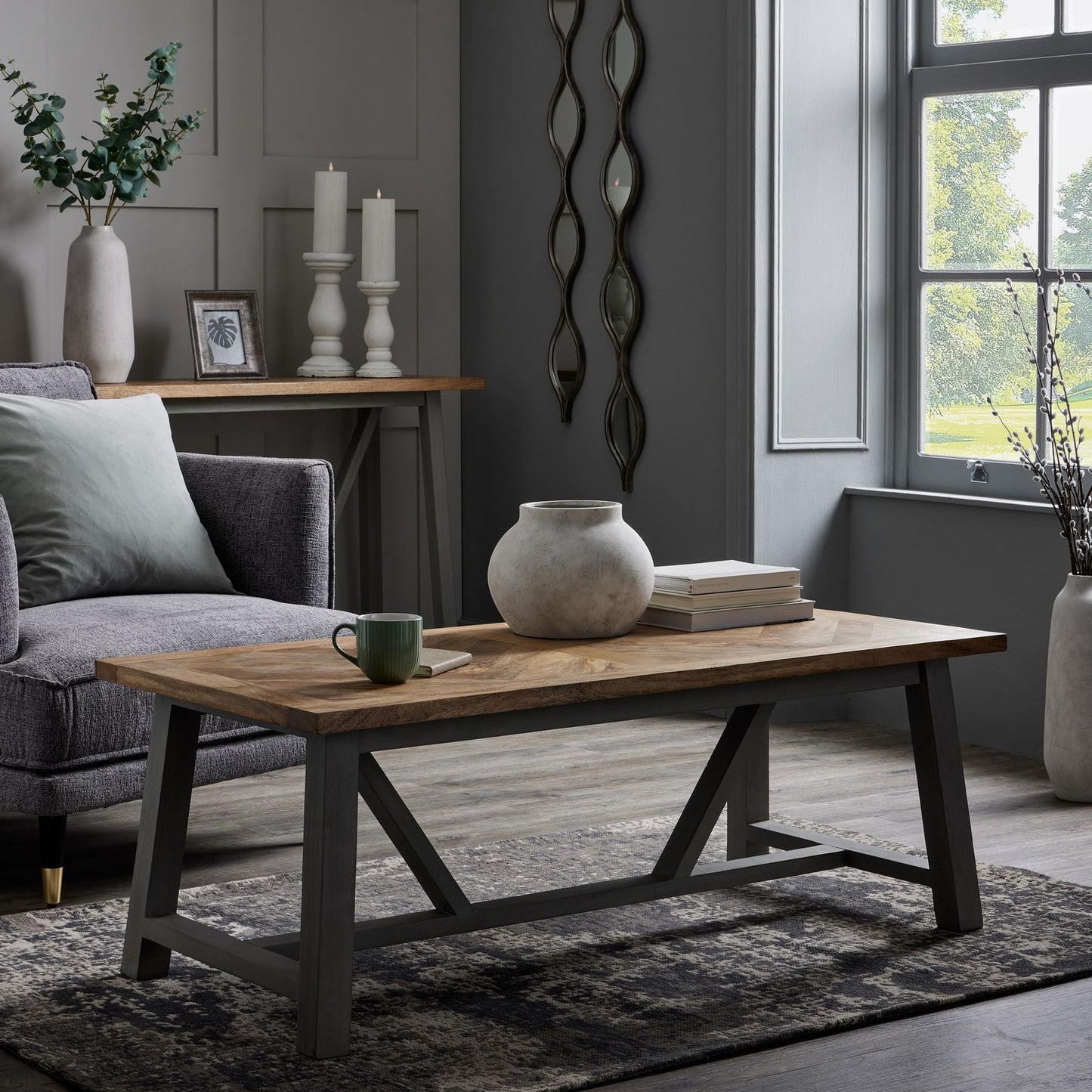 room set, two mirrors to the far wall, coffee table to the foreground, chair next to it and console table behind