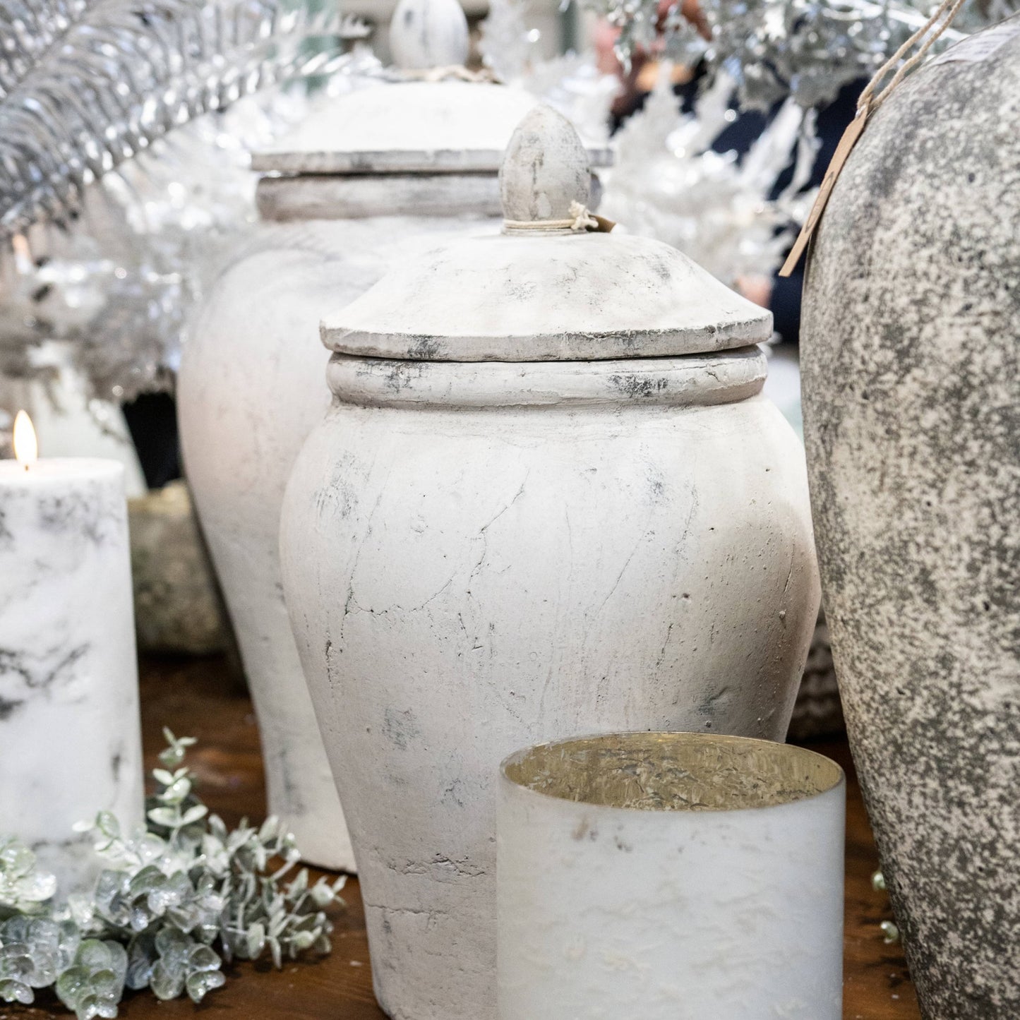 lifestyle image, small stone ginger jar with lid to the foreground and large behind. A frosted candle wreath and marble LED Candle are to the left