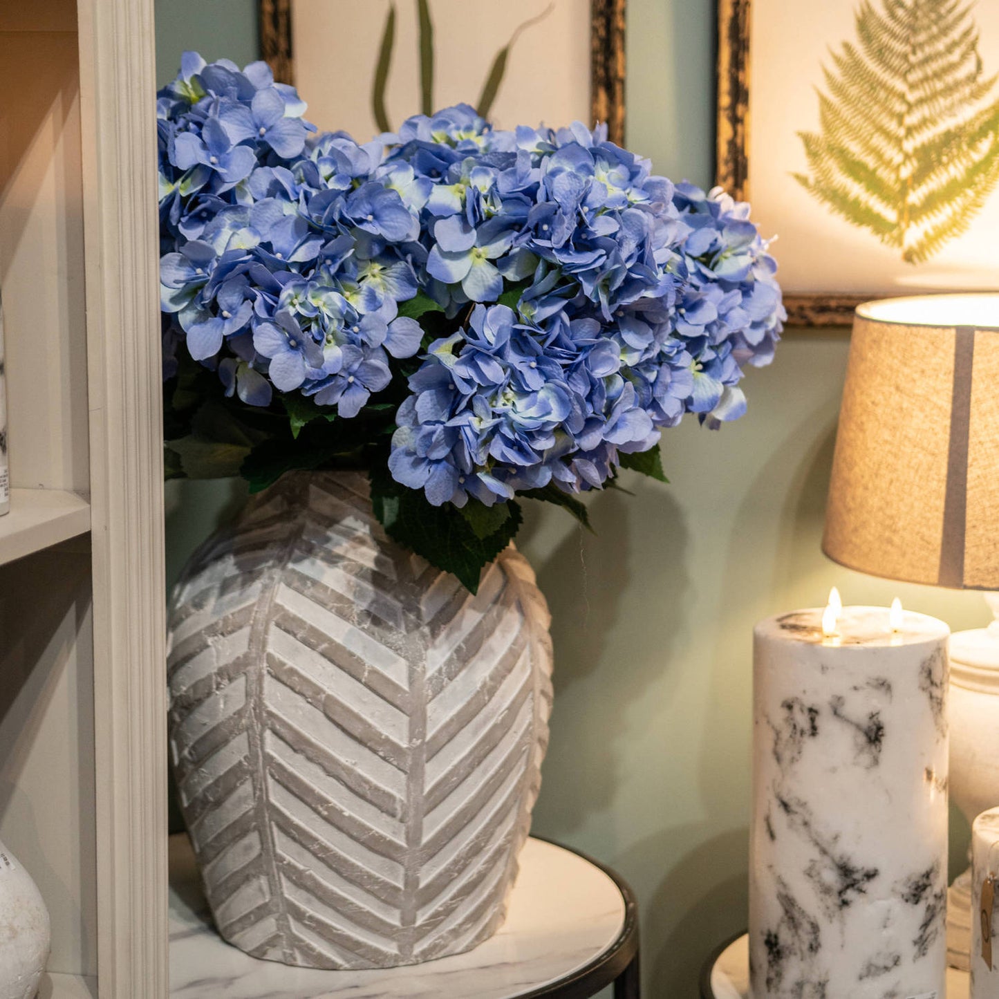 stone vase with lilac hydrangeas. Marble LED candle next it