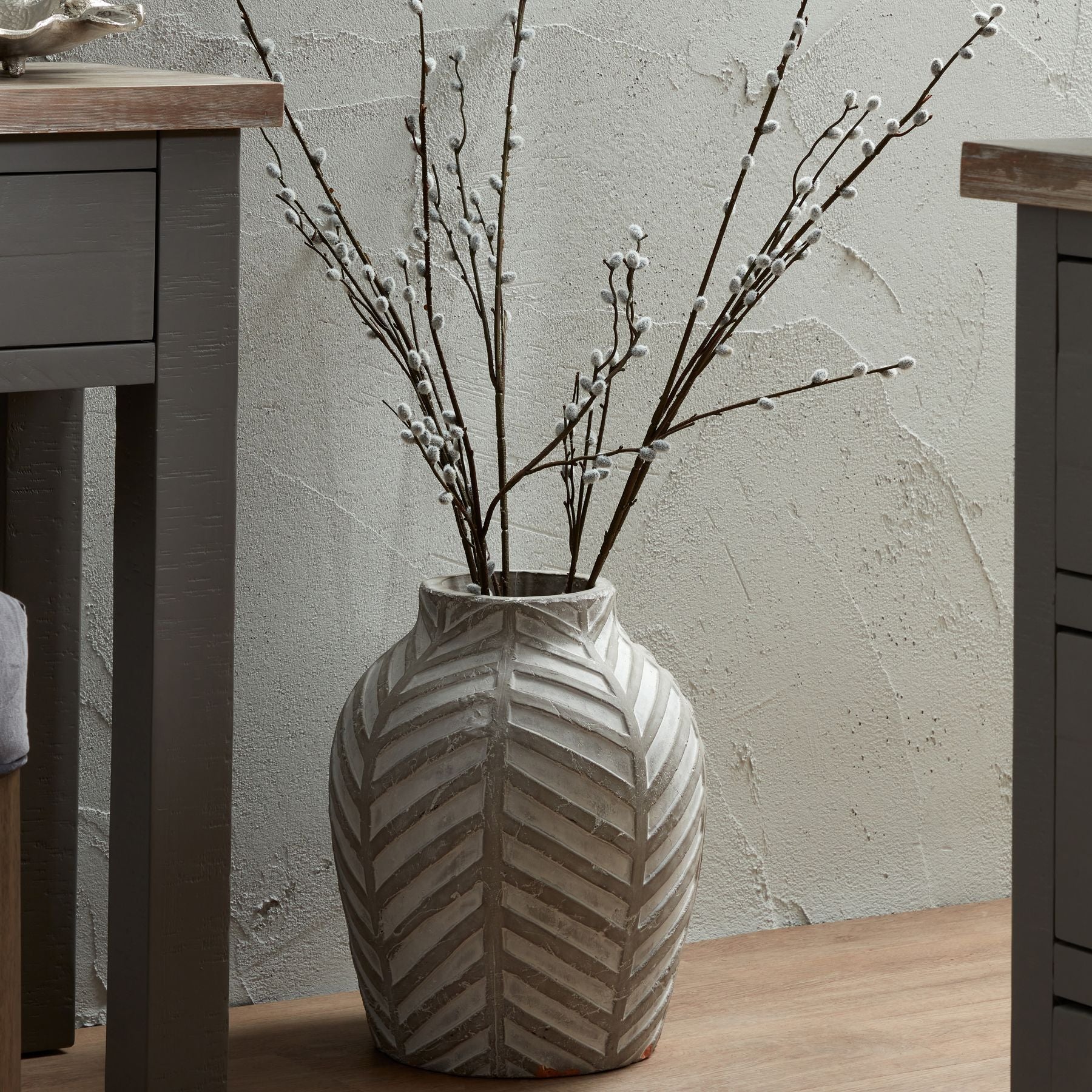 stone vase with branches, on floor next to console table