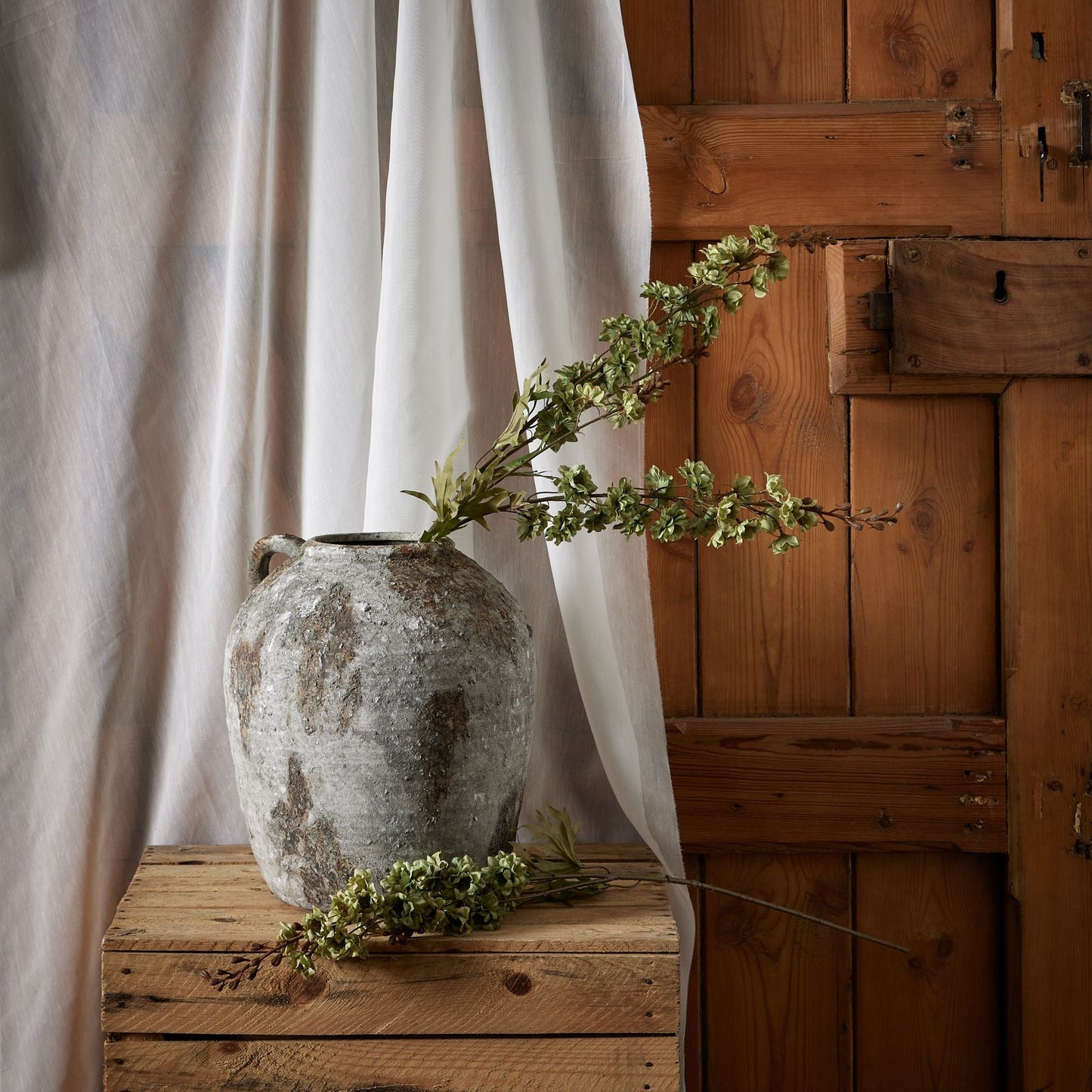 greens hops stem in aged stone vase