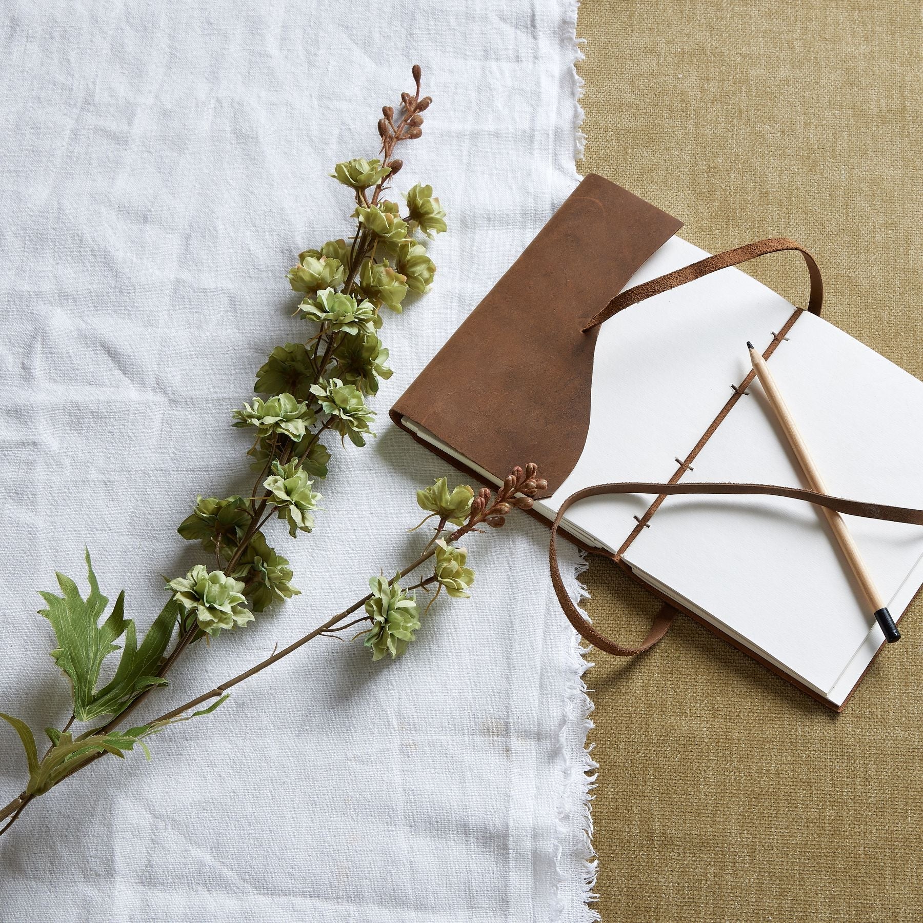 laid down green hops stem next to leather bound journal