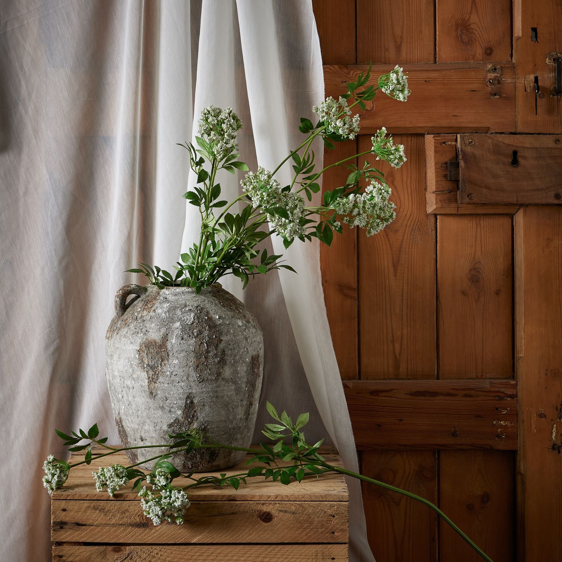 several stems in aged stone vase